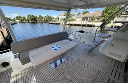  Yacht Photos Pics Luxury 2018 Prestige 680 yacht deck with seating and table, overlooking serene waterfront.