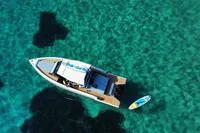 Aerial view of 2021 Scorpion 40 boat on clear turquoise water with paddleboard nearby.