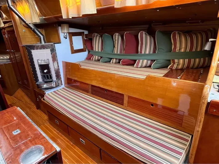 Perelandra Yacht Photos Pics Interior of a 1968 Hinckley Bermuda 40 sailboat with striped cushions and wood paneling.