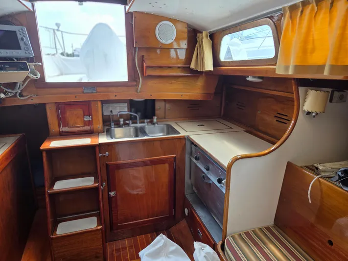 Perelandra Yacht Photos Pics Interior of a 1968 Hinckley Bermuda 40 sailboat, featuring a wooden galley with sink and stove.