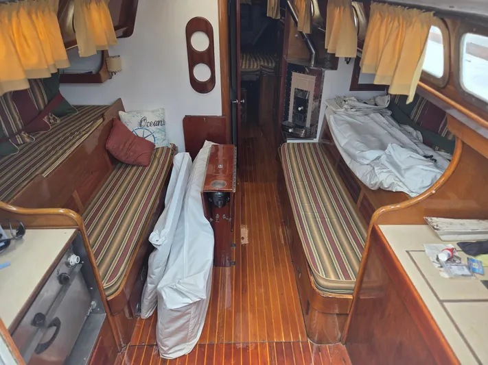 Perelandra Yacht Photos Pics Interior of a 1968 Hinckley Bermuda 40 sailboat with striped cushions and wooden flooring.