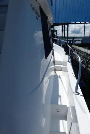  Yacht Photos Pics 1999 Mainship 350 Trawler side view with railing and dock background.