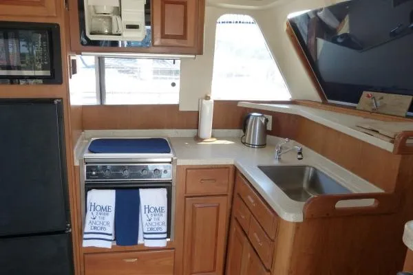  Yacht Photos Pics 1999 Mainship 350 Trawler kitchen with stove, sink, and wooden cabinetry.