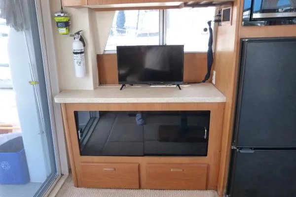  Yacht Photos Pics 1999 Mainship 350 Trawler interior with TV, fire extinguisher, and storage cabinets.