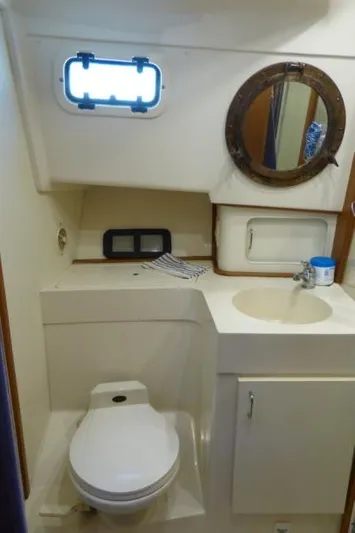  Yacht Photos Pics 1999 Mainship 350 Trawler bathroom with toilet, sink, and porthole window.