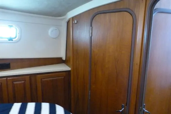  Yacht Photos Pics 1999 Mainship 350 Trawler cabin interior with wooden paneling and striped bedding.