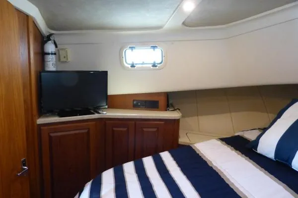  Yacht Photos Pics Cozy cabin interior of 1999 Mainship 350 Trawler with striped bedding and TV.