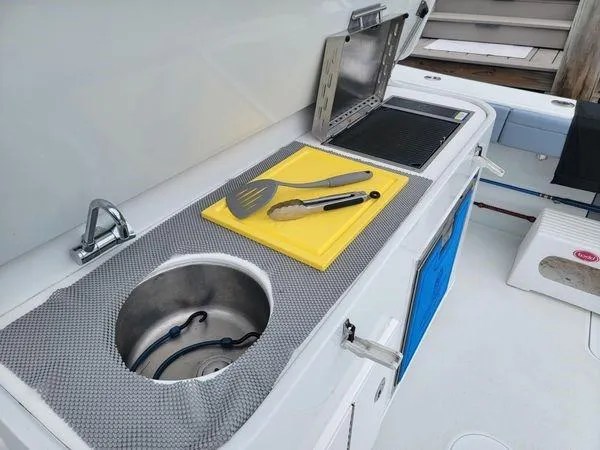  Yacht Photos Pics Outdoor kitchen on 2022 Yellowfin 42 Offshore boat with sink, grill, and utensils.
