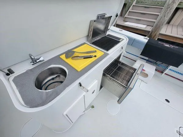  Yacht Photos Pics Outdoor kitchen on 2022 Yellowfin 42 Offshore boat with sink, grill, and storage.