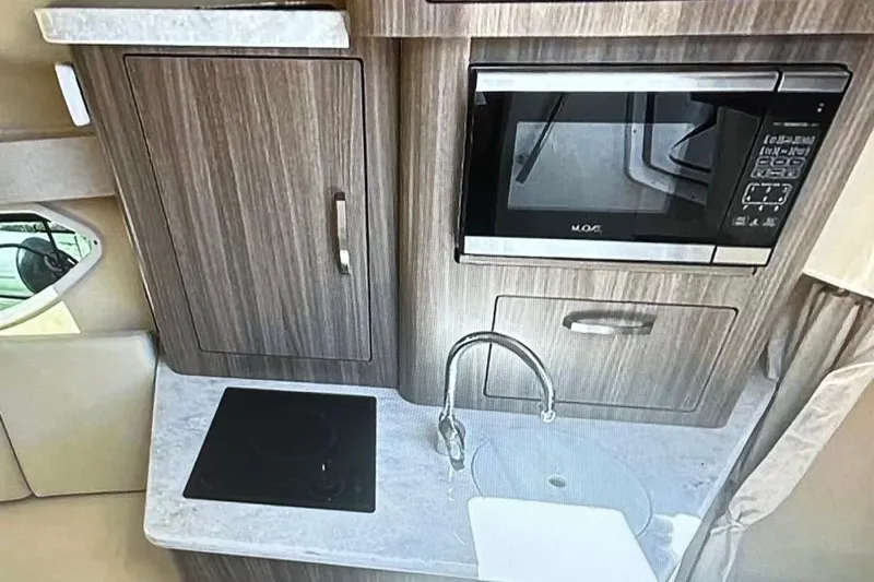  Yacht Photos Pics 2022 Regal 28 Express boat kitchen with microwave, sink, and stove.