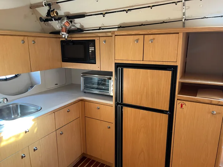  Yacht Photos Pics 2001 Tiara Yachts 4100 Open kitchen with wood cabinets, sink, microwave, and fridge.