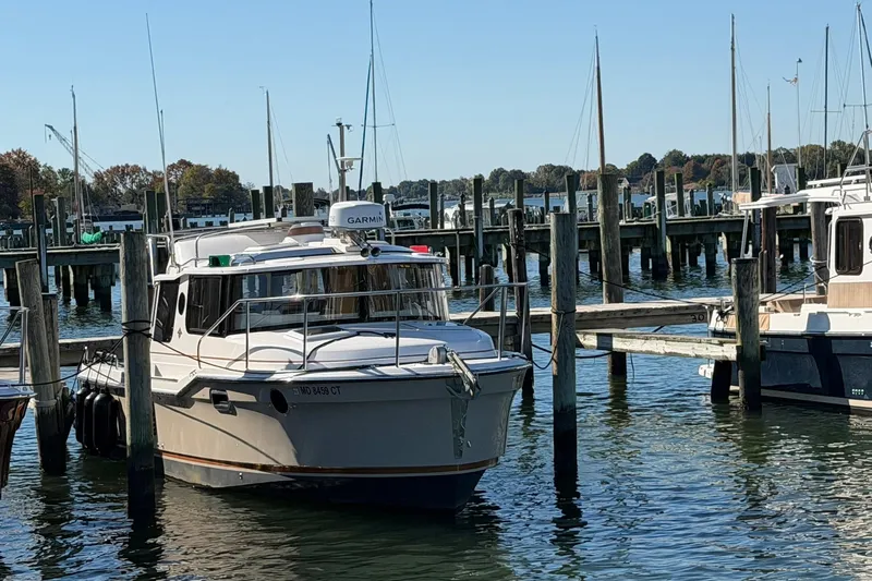 Getting There Yacht Photos Pics 2023 Ranger Tugs R-25 docked at a marina with sailboats in the background.
