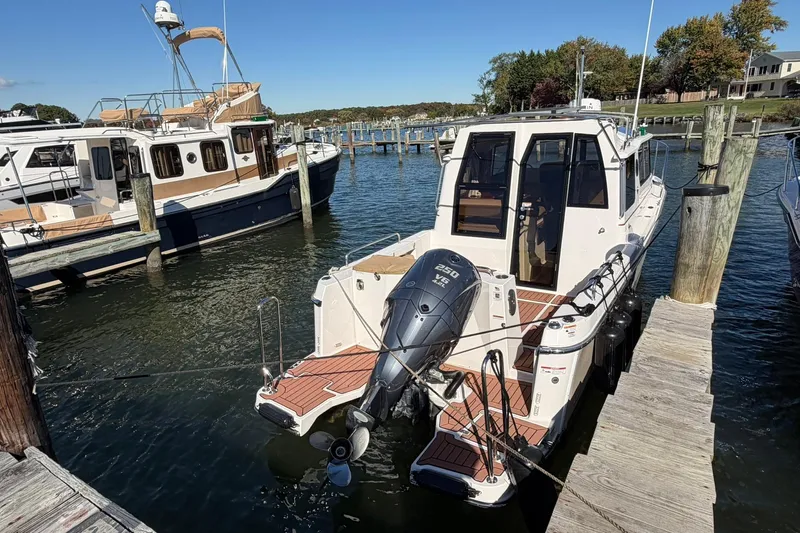 Getting There Yacht Photos Pics 2023 Ranger Tugs R-25 docked at marina, featuring outboard motor and spacious deck.