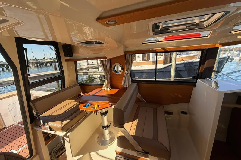 Getting There Yacht Photos Pics 2023 Ranger Tugs R-25 interior with seating, table, and windows overlooking marina.