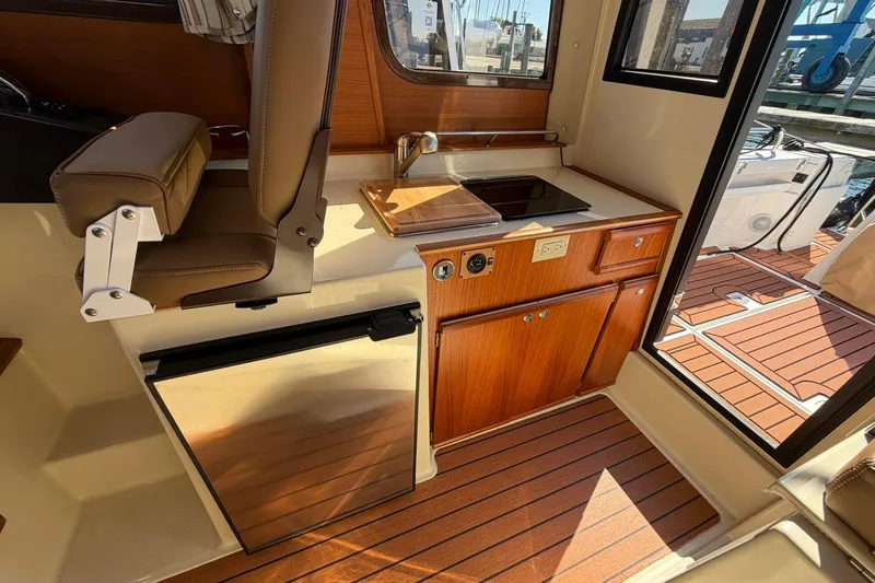 Getting There Yacht Photos Pics 2023 Ranger Tugs R-25 interior with kitchenette, wooden cabinetry, and seating.