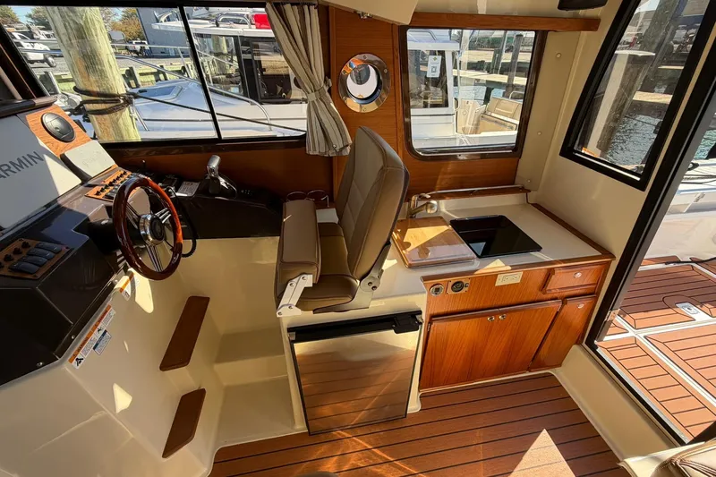 Getting There Yacht Photos Pics 2023 Ranger Tugs R-25 interior with helm, kitchenette, and wood accents.