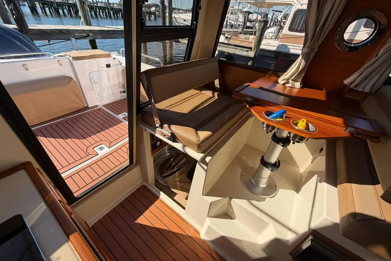 Getting There Yacht Photos Pics 2023 Ranger Tugs R-25 interior with wood accents and seating, docked by the water.