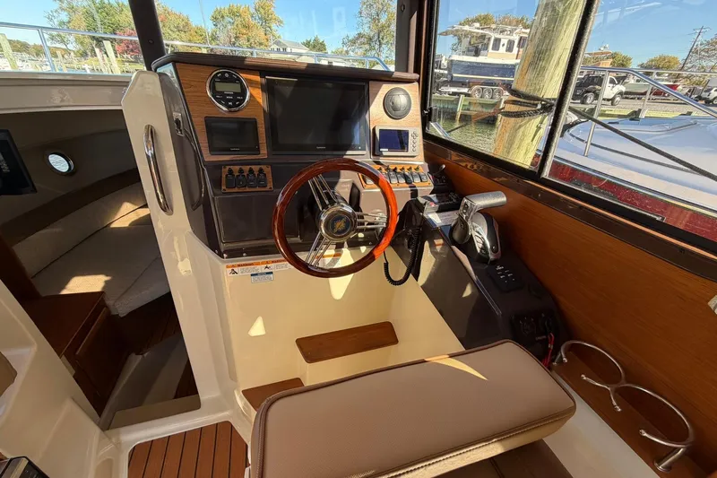 Getting There Yacht Photos Pics 2023 Ranger Tugs R-25 helm with wooden steering wheel and modern navigation controls.