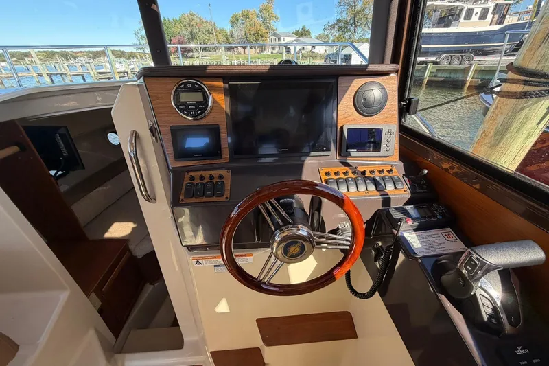 Getting There Yacht Photos Pics 2023 Ranger Tugs R-25 helm with modern navigation controls and wooden steering wheel.