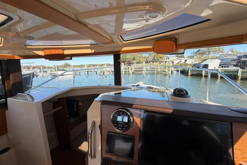 Getting There Yacht Photos Pics Interior view of 2023 Ranger Tugs R-25 boat, showcasing helm and waterfront scenery.
