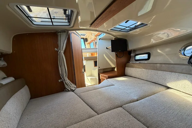 Getting There Yacht Photos Pics 2023 Ranger Tugs R-25 interior cabin with bed, skylights, and wooden accents.