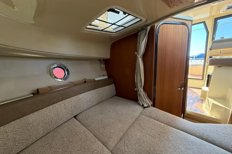 Getting There Yacht Photos Pics 2023 Ranger Tugs R-25 interior cabin with cozy bed and wooden door.