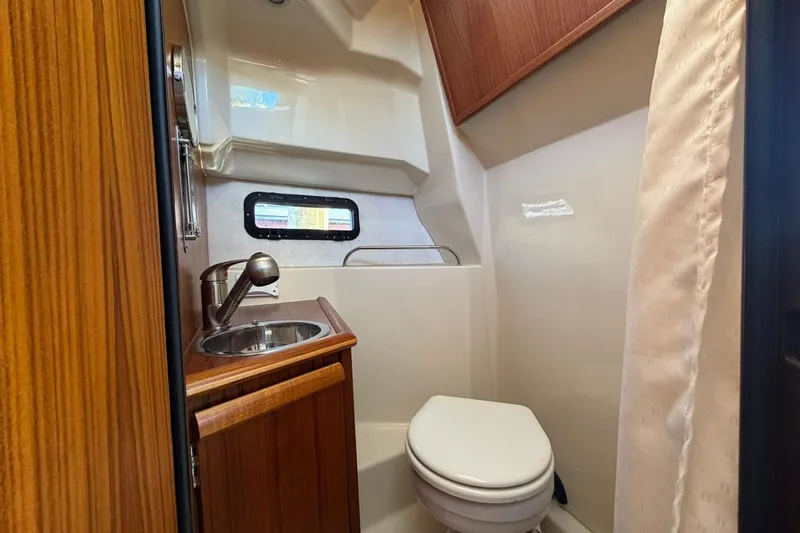 Getting There Yacht Photos Pics 2023 Ranger Tugs R-25 boat bathroom with sink, toilet, and wooden cabinetry.