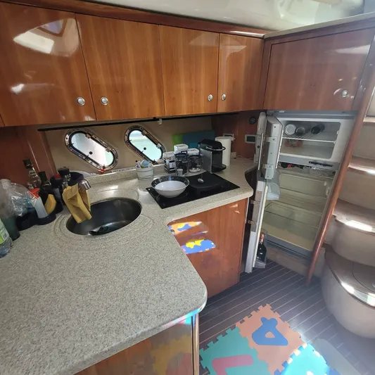  Yacht Photos Pics 2006 Cranchi Mediterranee 47 HT yacht kitchen with wooden cabinets, sink, and open fridge.