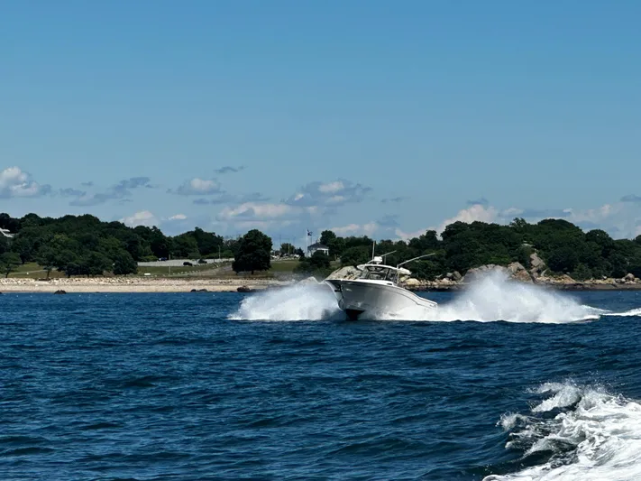 Katy Lady Yacht Photos Pics 2017 Grady-White Canyon 376 speeding on blue ocean near lush coastline.