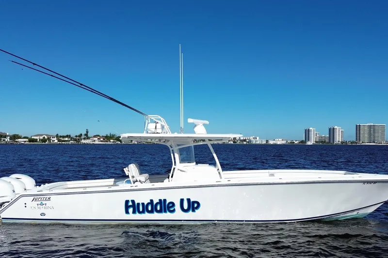 Huddle Up Yacht Photos Pics 2018 Jupiter 38 FS boat named "Huddle Up" on water with city skyline background.