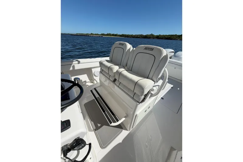 Huddle Up Yacht Photos Pics 2018 Jupiter 38 FS boat interior with dual seats, steering wheel, and ocean view.