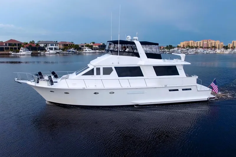 Cleodora Yacht Photos Pics 1988 Viking 63 Cockpit Motor Yacht cruising on calm waters, with a scenic marina backdrop.