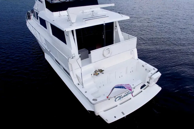 Cleodora Yacht Photos Pics 1988 Viking 63 Cockpit Motor Yacht on calm water, rear view with American flag.