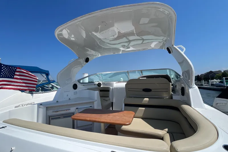  Yacht Photos Pics 2017 Rinker EX 370 boat interior with seating, table, and American flag in marina setting.