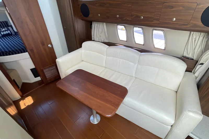  Yacht Photos Pics 2017 Rinker EX 370 yacht interior with white sofa, wooden table, and cabin windows.