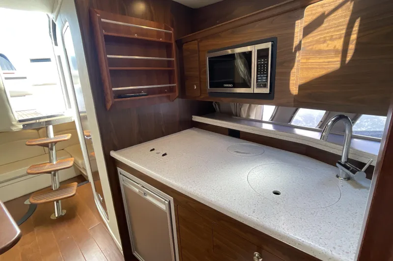  Yacht Photos Pics 2017 Rinker EX 370 yacht interior kitchen with microwave, sink, and wooden cabinetry.