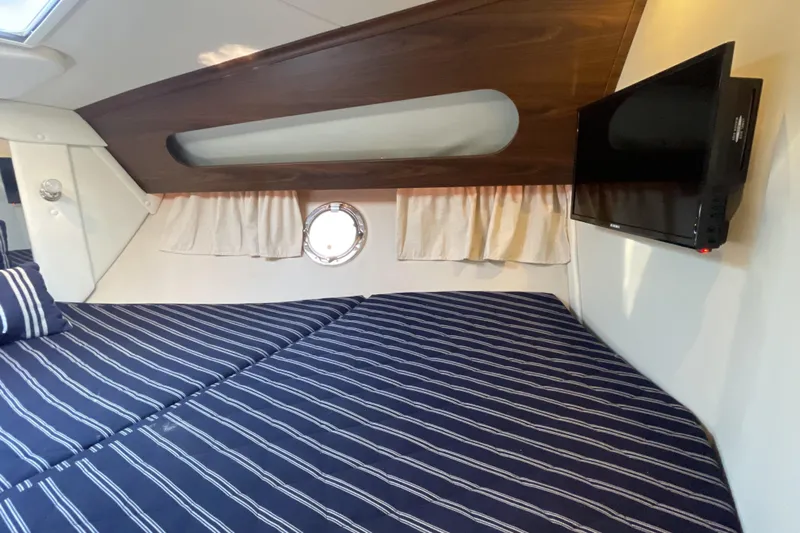 Yacht Photos Pics 2017 Rinker EX 370 cabin interior with striped bedding and wall-mounted TV.