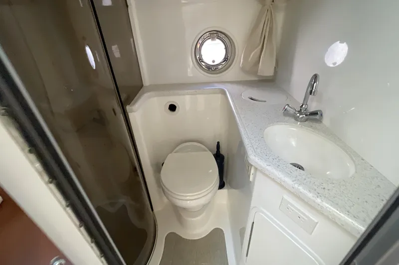  Yacht Photos Pics 2017 Rinker EX 370 boat bathroom with shower, toilet, sink, and porthole window.