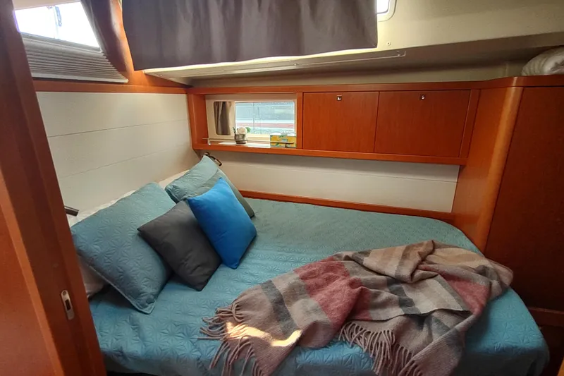 Indigo Sea Yacht Photos Pics Cozy cabin interior of 2018 Beneteau Sense 57 yacht with bed and window.