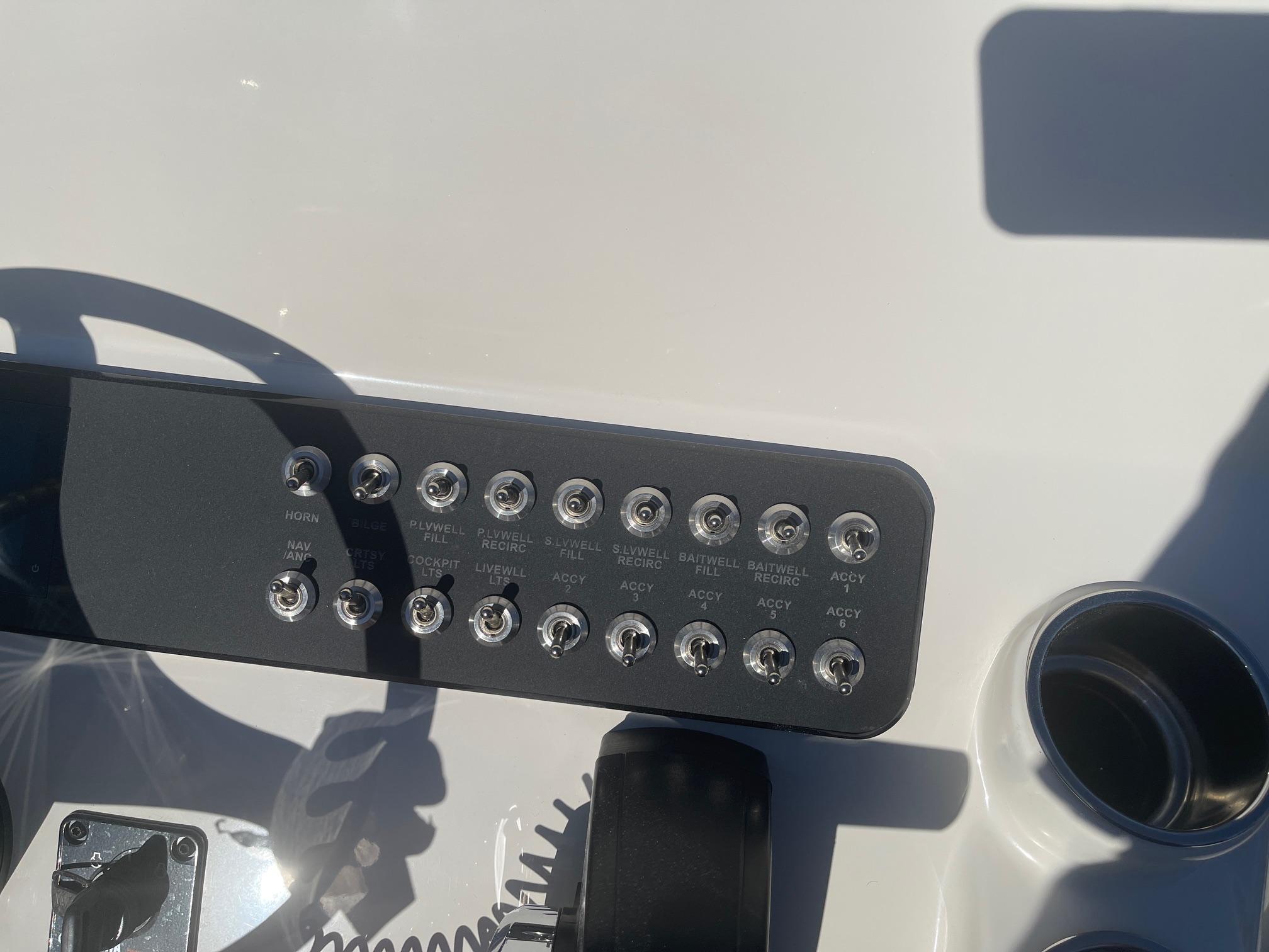 Control panel of 2025 Skeeter SX221 boat with labeled switches and cup holder.