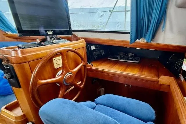 Mavi Yacht Photos Pics Interior of 1991 Oyster 49 yacht with wooden helm and blue seating.
