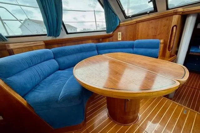 Mavi Yacht Photos Pics Luxurious interior of a 1991 Oyster 49 yacht with blue seating and wooden table.