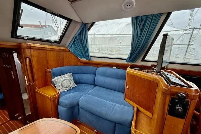 Mavi Yacht Photos Pics Interior of 1991 Oyster 49 yacht with blue sofa and wooden cabinetry.
