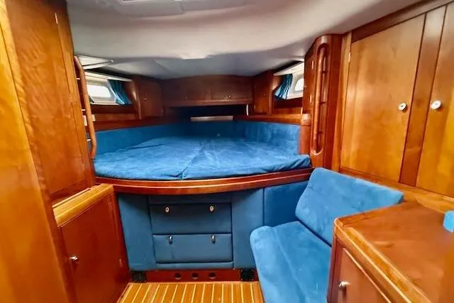Mavi Yacht Photos Pics Cozy cabin interior of a 1991 Oyster 49 yacht with blue upholstery and wooden finishes.