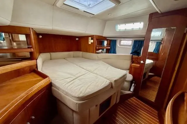 Mavi Yacht Photos Pics Luxurious cabin interior of a 1991 Oyster 49 yacht with wood finishes and cozy bedding.