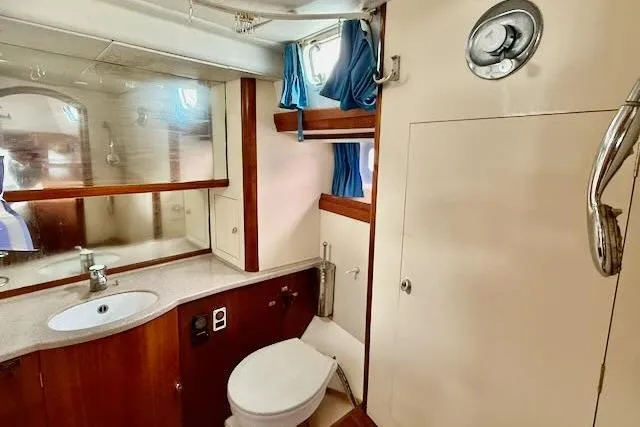 Mavi Yacht Photos Pics Bathroom interior of a 1991 Oyster 49 yacht, featuring wooden cabinetry and a compact design.