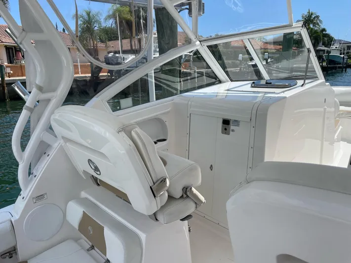  Yacht Photos Pics 2017 Edgewater 280 CX boat interior with white seating and dashboard, docked near waterfront homes.