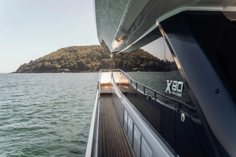 Chase Yacht Photos Pics 2023 Princess X80 yacht cruising near a lush island, showcasing sleek design and luxury.
