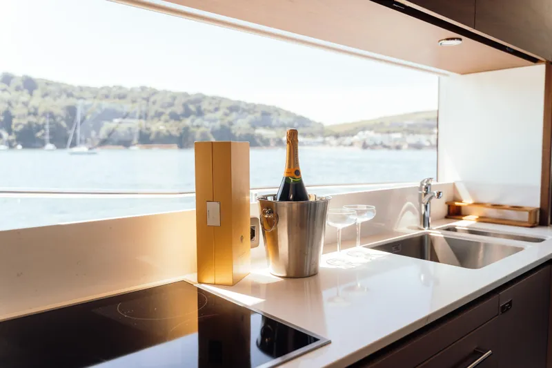 Chase Yacht Photos Pics Luxurious kitchen on 2023 Princess X80 yacht with champagne, overlooking scenic water view.