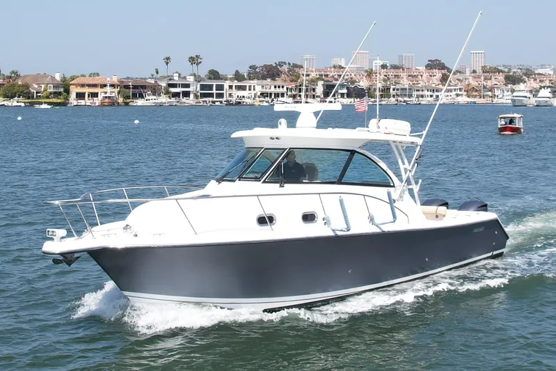 Hobi One Yacht Photos Pics 2015 Pursuit 345 Offshore boat cruising on a sunny day near coastal homes.